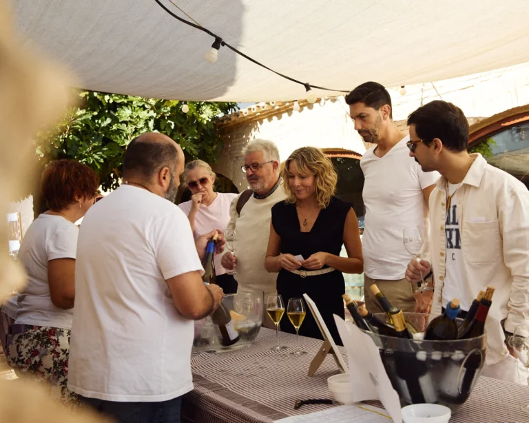 A group of people enjoying a Malvasia de Sitges tasting at an outdoor venue during the Malvasia Week.