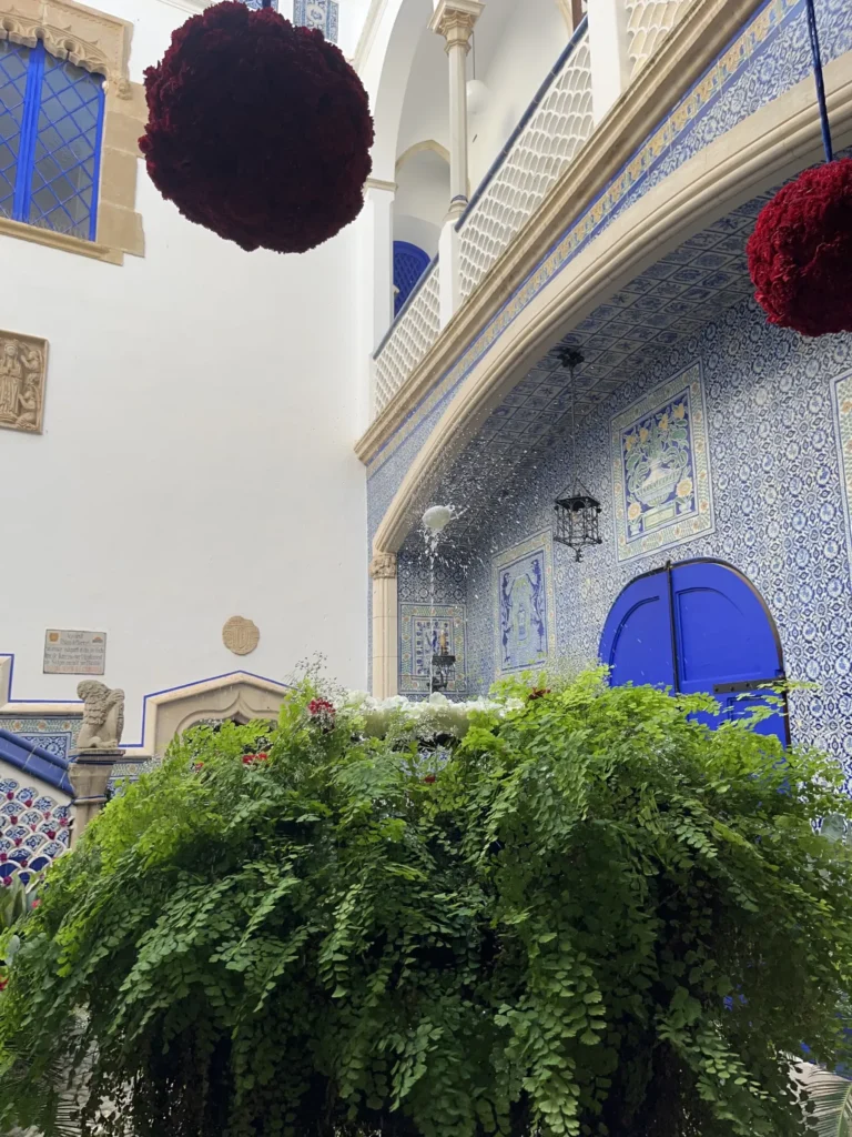 Interior courtyard of the Palau de Maricel in Sitges with blue tiles, lush vegetation and floral decoration, setting for the ou com balla tradition.