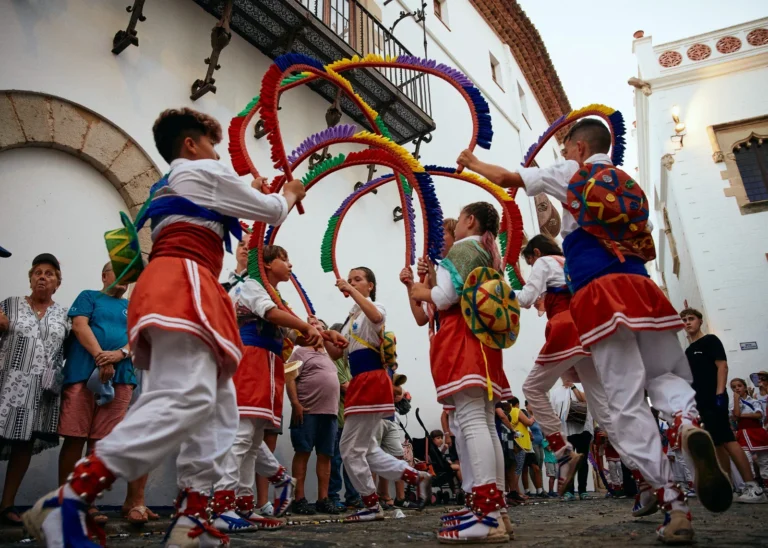 Children from Sitges performing the Cintes ribbon dance during the Diada de Sant Tecla, wearing colourful traditional costumes in the town square.