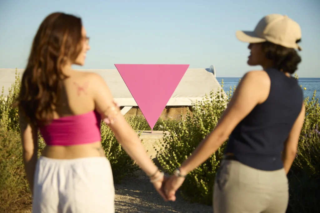 Una pareja de chicas ante el monumento LGTBI de Sitges