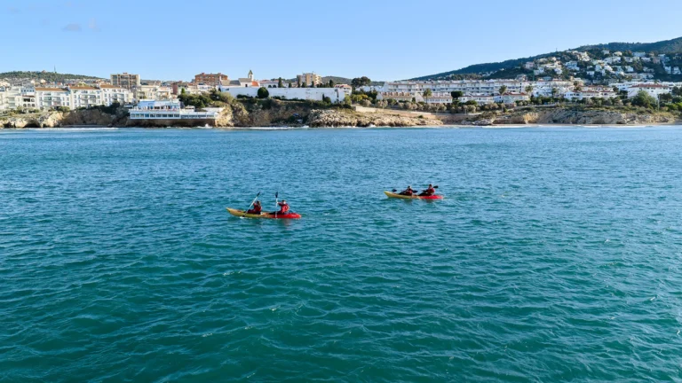 People kayaking between the coves of Sitges with the village in the background