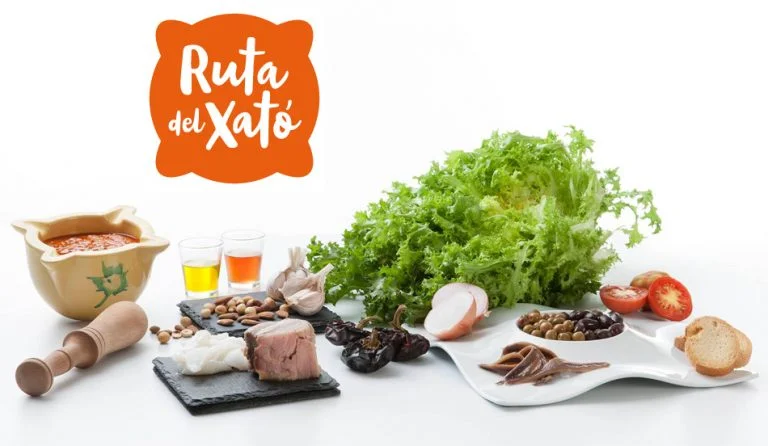 Xató ingredients — escarole, salt cod, tuna, anchovies, olives and romesco sauce — displayed with the Ruta del Xató de Sitges logo.